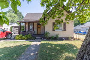 View of front facade with roof with shingles, a porch, and stucco siding