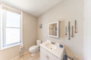 Bathroom with vanity, light tile patterned floors, and a textured wall