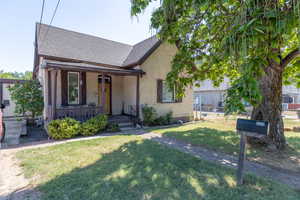 View of front of home featuring a shingled roof, a front yard, a porch, and stucco siding