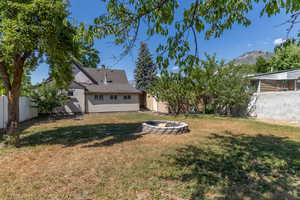 Rear view of property with an outdoor fire pit, a fenced backyard, a mountain view, and a shingled roof