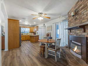 Dining space with dark wood finished floors, a ceiling fan, and a fireplace