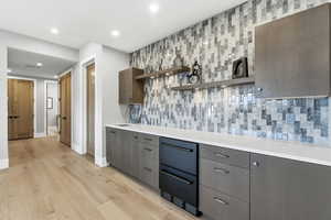 Kitchen with open shelves, modern cabinets, decorative backsplash, light wood-style flooring, and recessed lighting