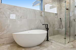 Bathroom with a freestanding tub, a marble finish shower, tile walls, and marble tiled flooring