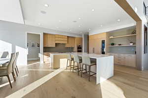 Kitchen featuring a kitchen breakfast bar, open shelves, a spacious island, recessed lighting, and light stone countertops