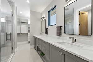 Bathroom featuring double vanity, a spacious closet, recessed lighting, a stall shower, and plenty of natural light