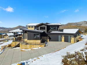 Contemporary home with a mountain view, stone siding, concrete driveway, and a garage