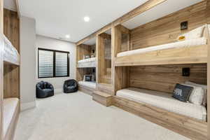 Carpeted bedroom with wood walls and recessed lighting