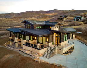 View of front of property with a standing seam roof, a metal roof, driveway, a mountain view, and stone siding