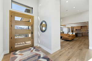 Foyer with healthy amount of natural light, a high ceiling, recessed lighting, and light wood-type flooring