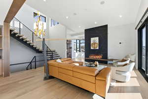 Living area featuring a high end fireplace, light wood-style floors, recessed lighting, a high ceiling, and stairs