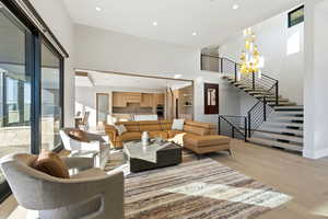 Living room featuring stairs, light wood-type flooring, recessed lighting, and a high ceiling