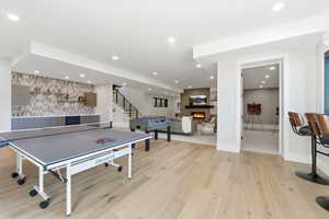 Recreation room featuring a large fireplace, light wood-style floors, recessed lighting, and an accent wall