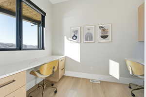 Office area with built in desk and light wood-type flooring