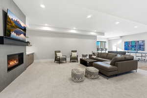 Living room with recessed lighting, a glass covered fireplace, and light colored carpet