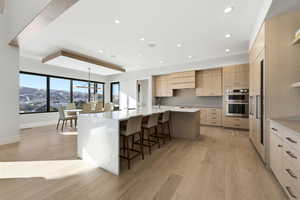 Kitchen featuring a breakfast bar, a large island, pendant lighting, light stone counters, and recessed lighting
