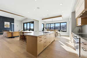 Kitchen featuring custom exhaust hood, light wood finished floors, light stone counters, oven, and recessed lighting