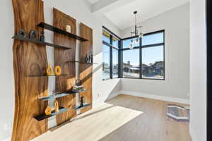 Unfurnished dining area with light wood-type flooring, lofted ceiling, and a chandelier