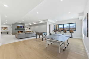 Recreation room with light wood-style flooring, a large fireplace, and recessed lighting