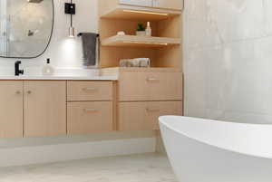 Full bath with vanity, a freestanding bath, and tile walls