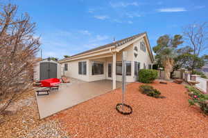 Rear view of house with a shed, a patio area, and stucco siding