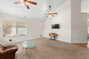 Living area featuring carpet floors, high vaulted ceiling, and a ceiling fan