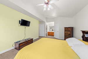 Carpeted bedroom with lofted ceiling, a ceiling fan, and ensuite bathroom