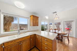Kitchen with brown cabinets, a peninsula, light countertops, a mountain view, and light wood finished floors