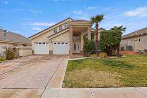 View of front of property with stucco siding, decorative driveway, brick siding, and an attached garage