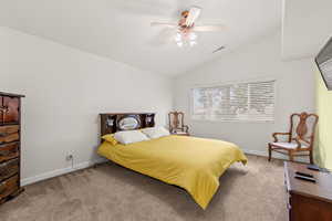 Bedroom with vaulted ceiling, carpet floors, and a ceiling fan