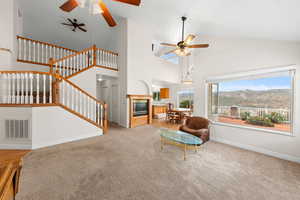 Living room with carpet, high vaulted ceiling, stairway, and ceiling fan