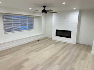 Unfurnished living room featuring recessed lighting, light wood finished floors, a fireplace, and a ceiling fan