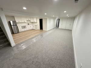 Unfurnished living room with light colored carpet, stairs, and recessed lighting