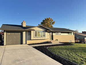 Ranch-style home featuring brick siding, a front lawn, concrete driveway, and a chimney
