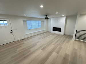 Unfurnished living room with recessed lighting, light wood-style floors, a large fireplace, and ceiling fan