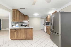 Kitchen with stainless steel refrigerator with ice dispenser, ornamental molding, a peninsula, brown cabinetry, and tasteful backsplash