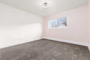 Carpeted spare room featuring baseboards