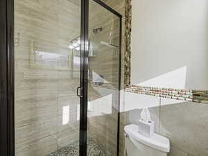 Full bathroom with a shower stall, french doors, and tile walls