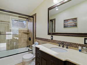 Full bath featuring vanity, combined bath / shower with glass door, and tile walls