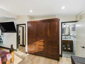 Bedroom featuring light wood-type flooring, recessed lighting, connected bathroom, and vaulted ceiling