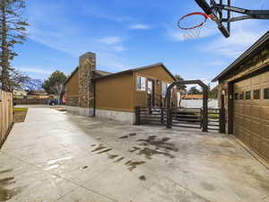 View of property exterior featuring stucco siding, a garage, stone siding, a chimney, and driveway