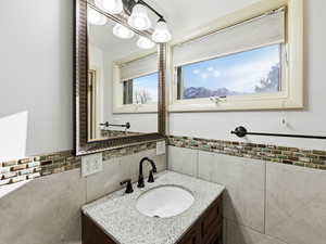 Bathroom with vanity, a wainscoted wall, and tile walls