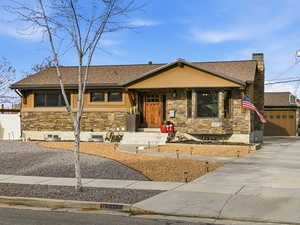 View of front of home with stone siding, roof with shingles, a porch, and stucco siding