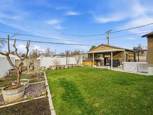 Fenced backyard featuring a vegetable garden and a patio