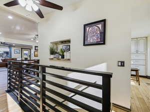 Hall featuring light wood-style floors, an upstairs landing, and recessed lighting