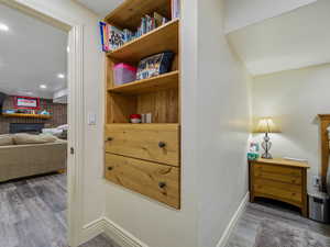 Detailed view of wood finished floors, a brick fireplace, and recessed lighting