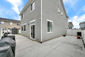 View of property exterior featuring a gate, a storage shed, and stucco siding