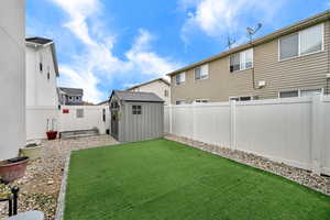 Fenced backyard featuring a storage unit