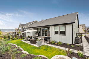 Rear view of property with a shingled roof, a patio, an outdoor hangout area, and board and batten siding