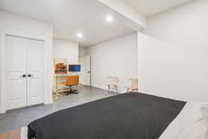 Bedroom with concrete flooring, built in study area, recessed lighting, and a closet