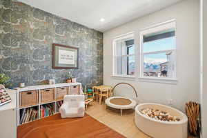 Living area featuring wood finished floors, wallpapered walls, an accent wall, and a textured ceiling